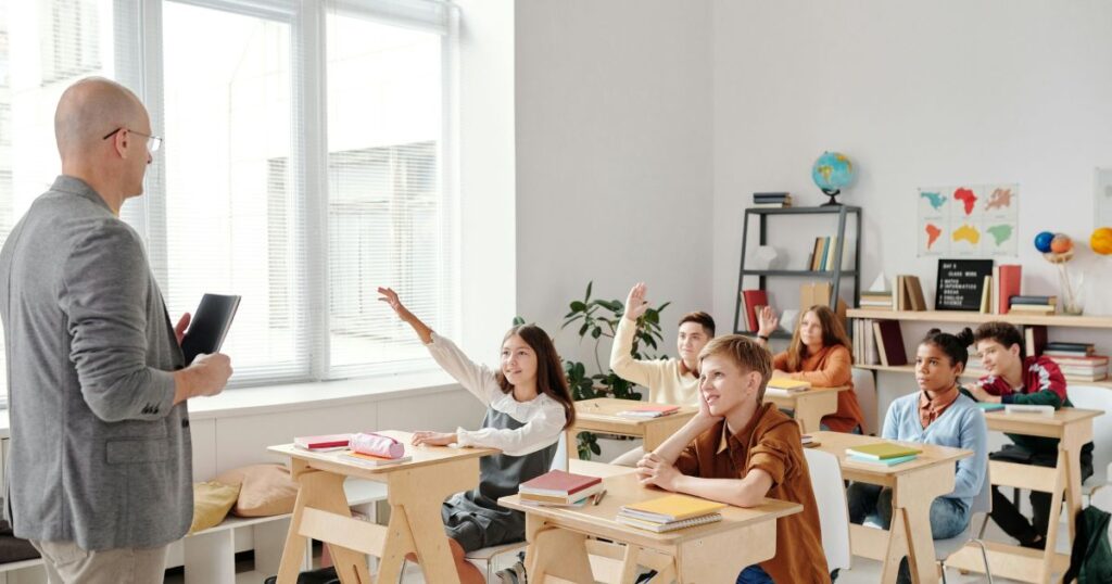 This shows the holistic development in education. A teacher is teaching in a classroom. Students are very happy to attend the class.