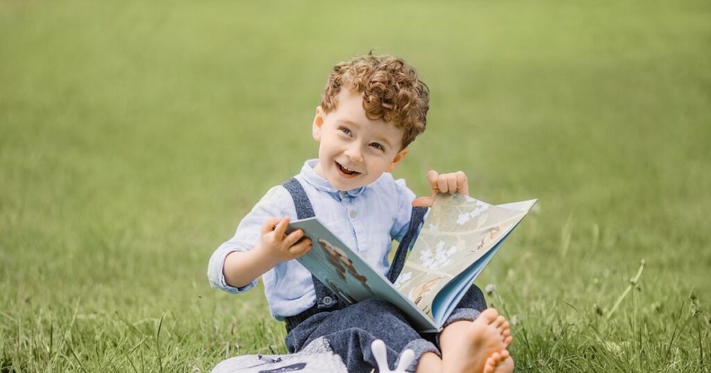 A little boy is sitting on the grass and doing constructive learning